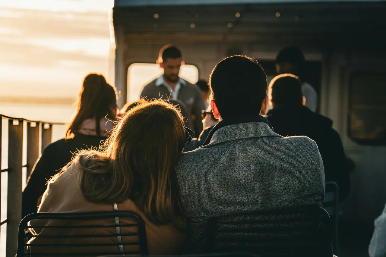Two people sitting close together on a bench in the evening