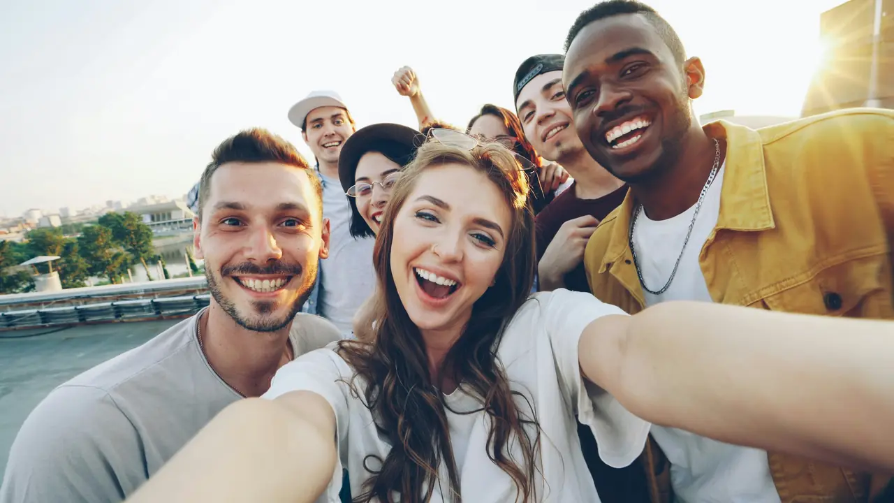 A group of smiling friends squeezing into a selfie on a sunny day