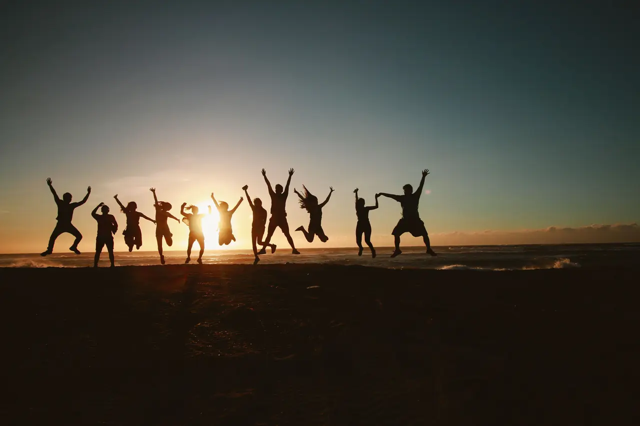 Friends jumping with their arms in the air against a glowing sunset