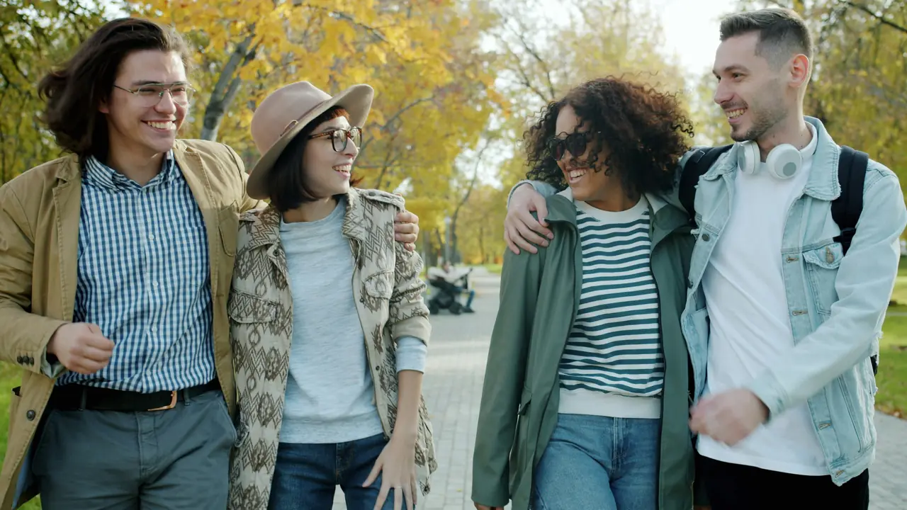 Four friends walking and laughing down an autumn street